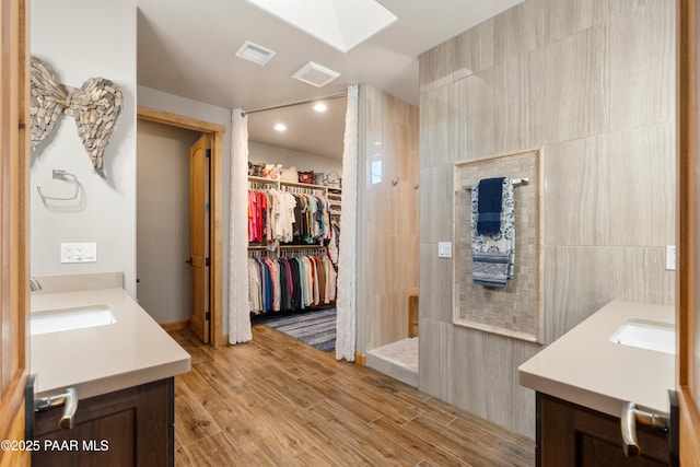 bathroom with vanity, a shower, tile walls, and a skylight