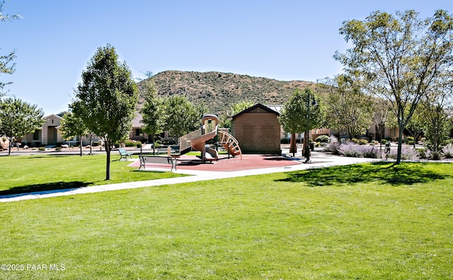 surrounding community with a playground, a mountain view, and a lawn