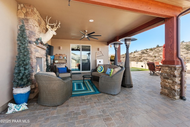 view of patio with an outdoor living space with a fireplace and ceiling fan