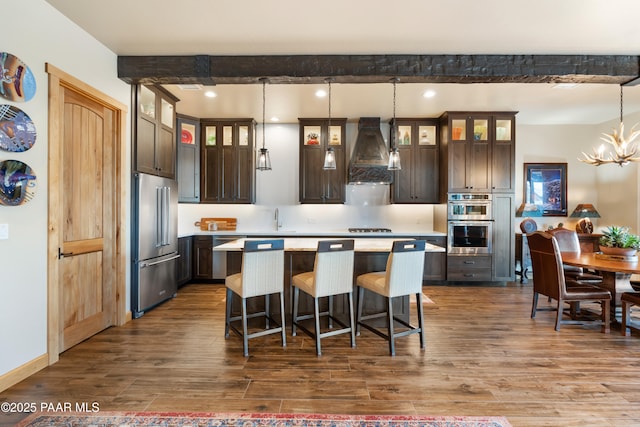 kitchen with dark brown cabinets, stainless steel appliances, a center island, and hanging light fixtures