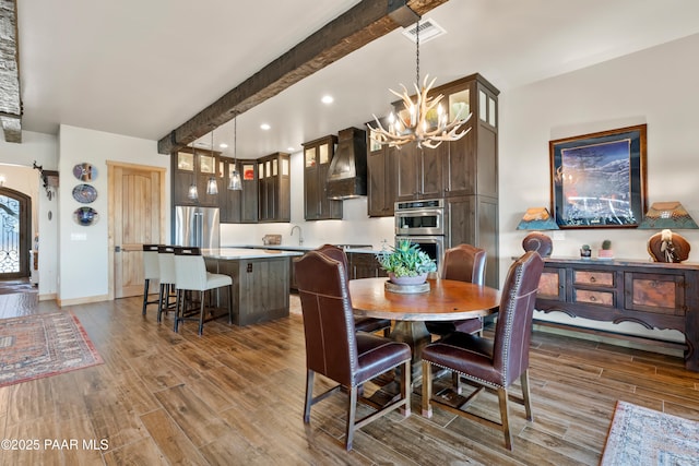 dining area featuring beamed ceiling, an inviting chandelier, and light wood-type flooring