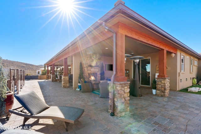 rear view of property with a mountain view, exterior fireplace, and a patio area