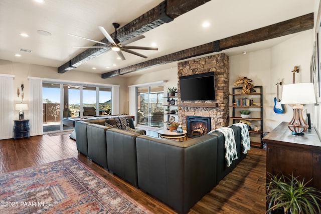 living room featuring beamed ceiling, a healthy amount of sunlight, a fireplace, and dark hardwood / wood-style flooring