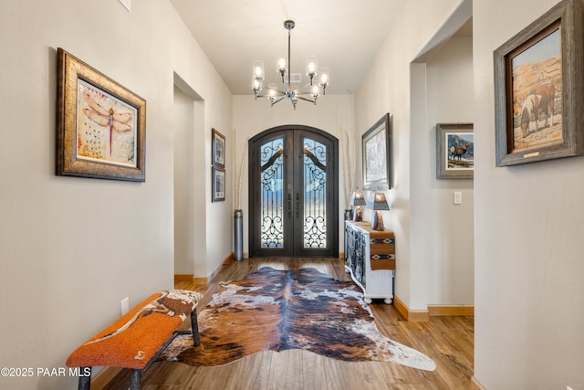 entryway with an inviting chandelier, light hardwood / wood-style flooring, and french doors