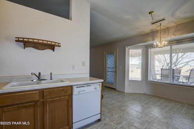 kitchen with brown cabinetry, visible vents, white dishwasher, a sink, and hanging light fixtures