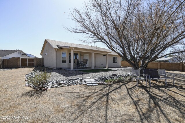 rear view of house featuring a patio area, stucco siding, and a fenced backyard