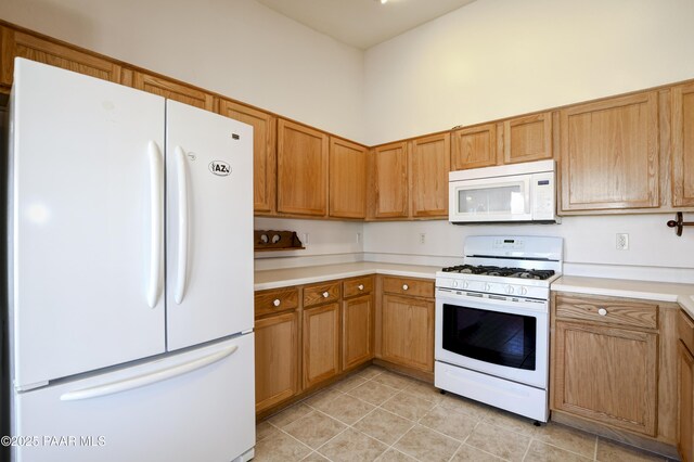 kitchen with white appliances, a high ceiling, light tile patterned floors, and light countertops