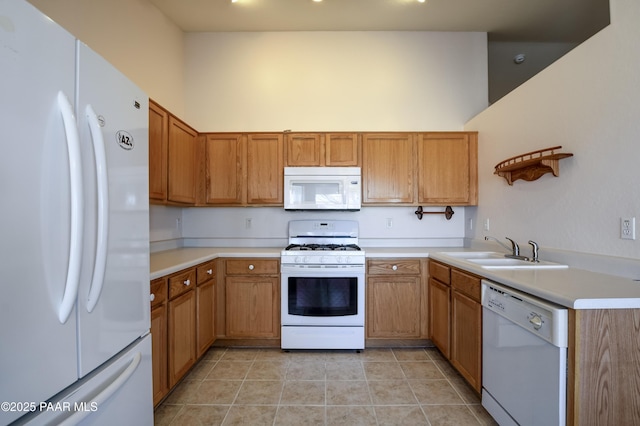 kitchen with light countertops, a towering ceiling, light tile patterned flooring, white appliances, and a sink