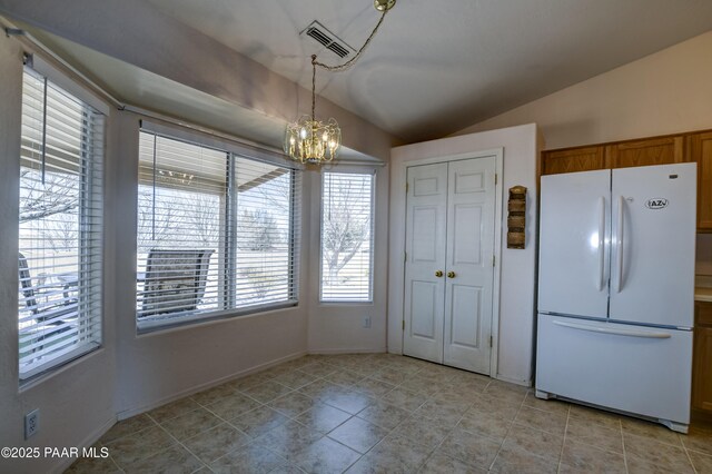 kitchen with visible vents, brown cabinets, pendant lighting, freestanding refrigerator, and vaulted ceiling