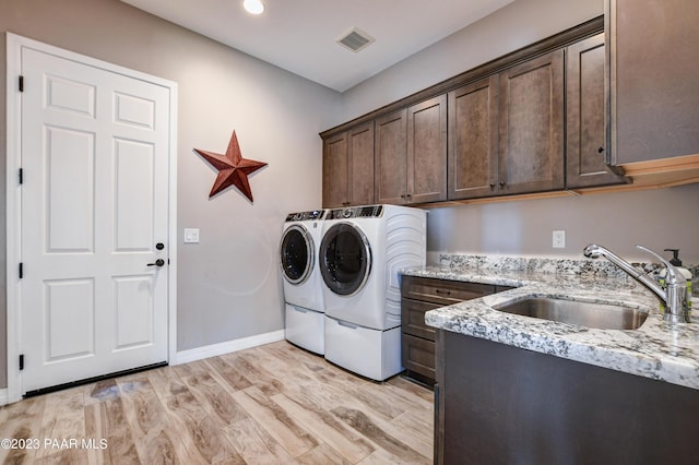 laundry room featuring cabinets, light hardwood / wood-style floors, washing machine and clothes dryer, and sink