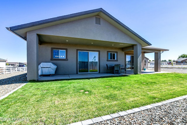 rear view of house with a patio and a lawn