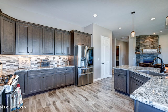 kitchen featuring dark brown cabinetry, sink, pendant lighting, and stainless steel refrigerator with ice dispenser