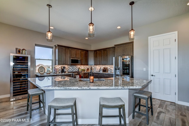 kitchen with wine cooler, sink, decorative light fixtures, and appliances with stainless steel finishes