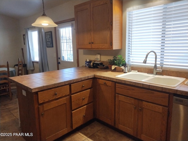 kitchen featuring sink, hanging light fixtures, tile patterned flooring, stainless steel dishwasher, and tile counters