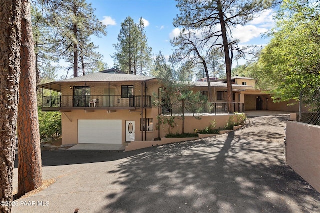 4937 S Deer Trl, Prescott, AZ 86303 - view of front of house with asphalt driveway, a balcony, a garage, stucco siding, and brick siding