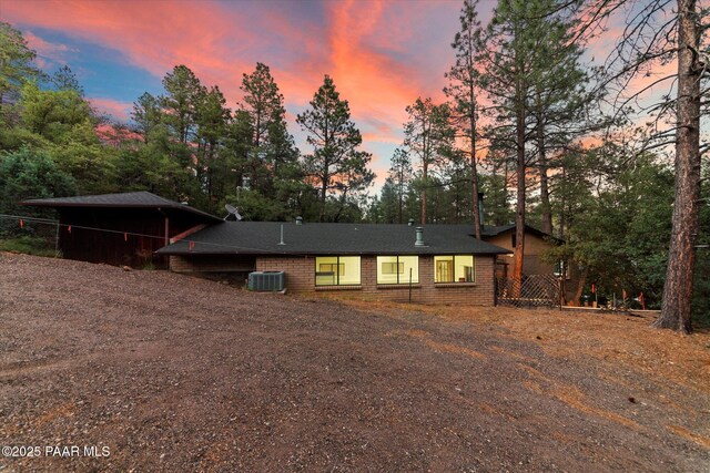 4937 S Deer Trl, Prescott, AZ 86303 - view of front of home featuring central AC, dirt driveway, brick siding, and view of scattered trees