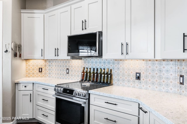 kitchen featuring light stone countertops, decorative backsplash, stainless steel appliances, and white cabinets