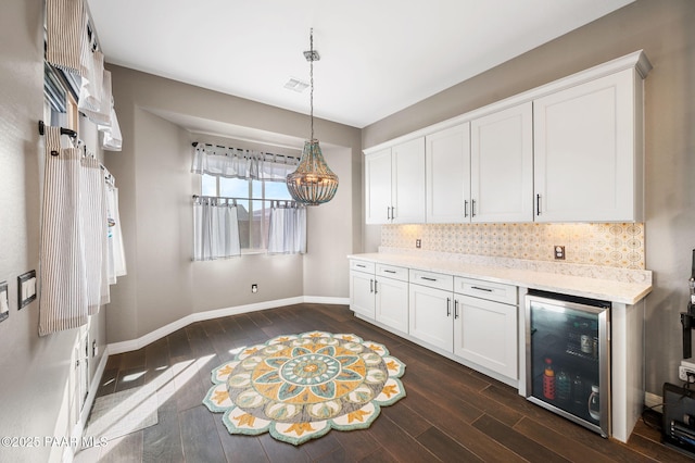 kitchen with decorative light fixtures, dark hardwood / wood-style floors, white cabinets, beverage cooler, and backsplash