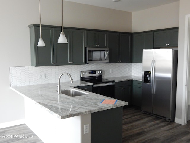 kitchen featuring dark wood-type flooring, sink, hanging light fixtures, kitchen peninsula, and stainless steel appliances