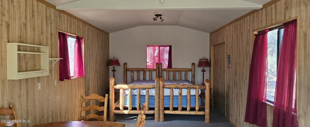 bedroom with multiple windows, vaulted ceiling, wood walls, and carpet