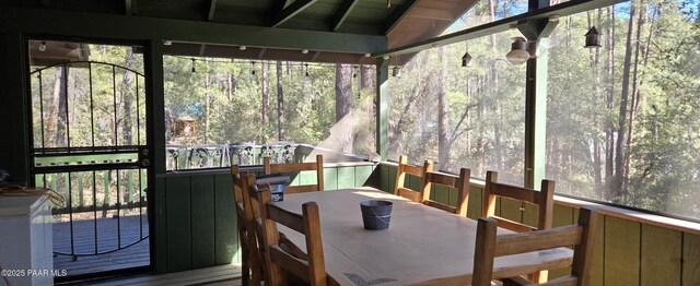 sunroom featuring vaulted ceiling, outdoor dining space, and a deck