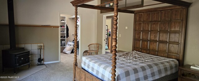 bedroom with light carpet, a closet, a walk in closet, and a wood stove