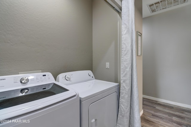 clothes washing area featuring wood-type flooring and washing machine and clothes dryer