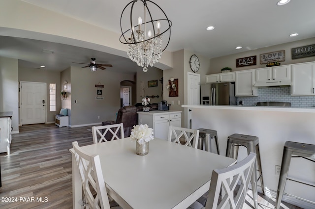 dining room with hardwood / wood-style floors and ceiling fan with notable chandelier