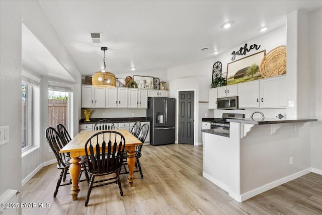 kitchen with dark countertops, stainless steel appliances, a peninsula, and visible vents