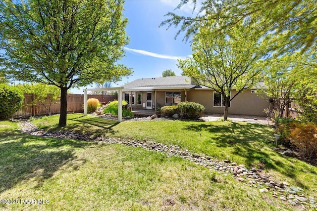 back of property with fence, stucco siding, a yard, and a patio area