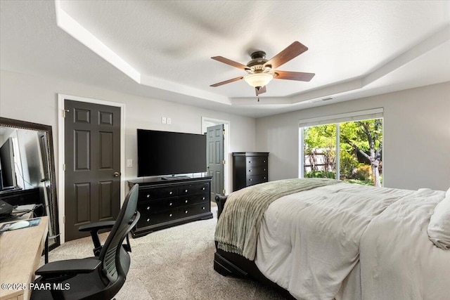 bedroom with a raised ceiling, a ceiling fan, carpet flooring, and visible vents