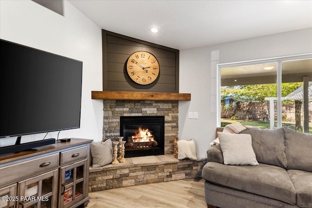 living room featuring a stone fireplace, recessed lighting, and wood finished floors
