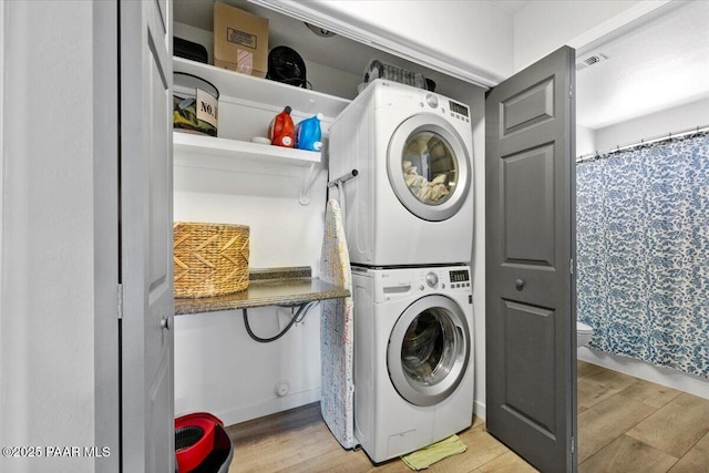 laundry room with visible vents, stacked washer / drying machine, light wood finished floors, and laundry area