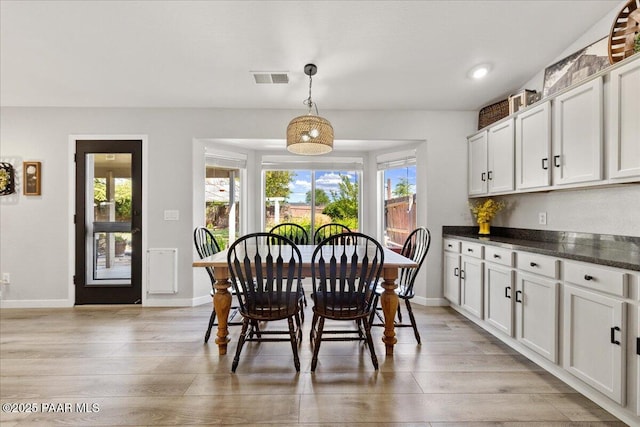 dining area featuring baseboards, visible vents, light wood finished floors, and a wealth of natural light
