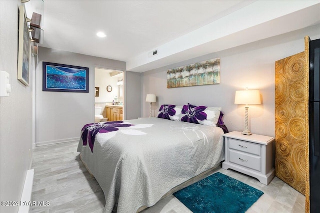 bedroom with light hardwood / wood-style floors and ensuite bath