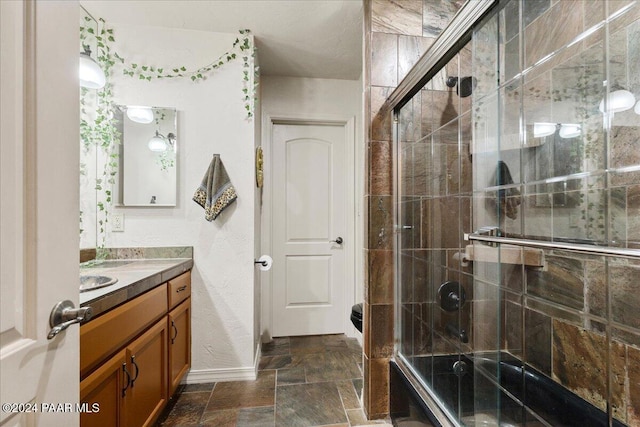 bathroom with a shower with door, vanity, and toilet