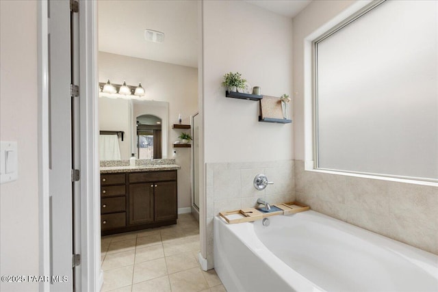 bathroom with tile patterned floors, a bathing tub, and vanity