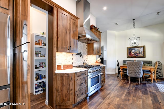 kitchen with an inviting chandelier, ventilation hood, stainless steel appliances, decorative light fixtures, and dark hardwood / wood-style flooring