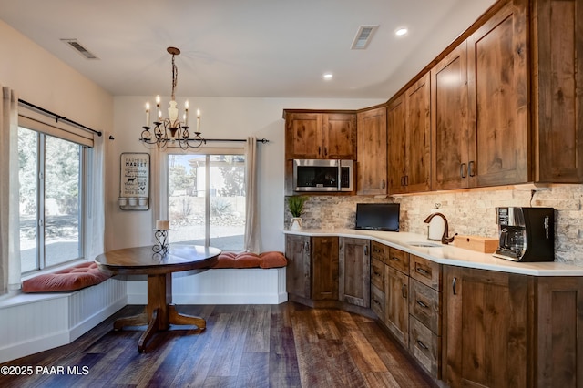 kitchen with breakfast area, decorative light fixtures, dark wood-type flooring, backsplash, and a notable chandelier