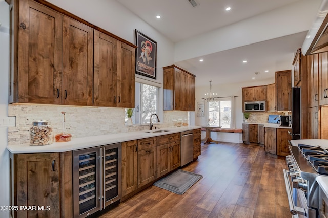 kitchen featuring stainless steel appliances, backsplash, wine cooler, hanging light fixtures, and sink