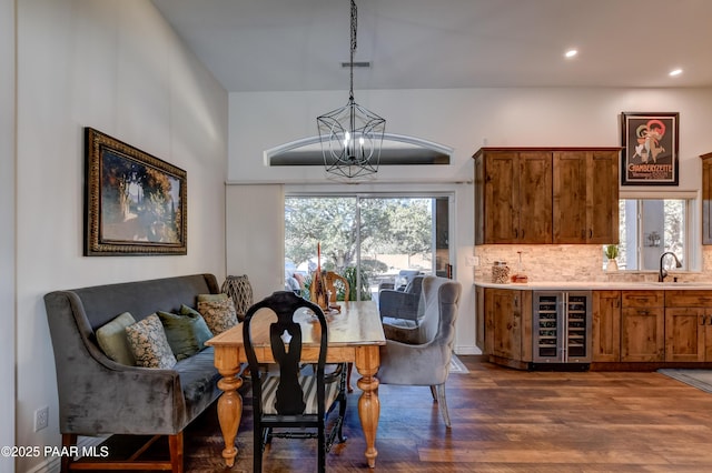 dining area with sink, dark hardwood / wood-style flooring, beverage cooler, and an inviting chandelier