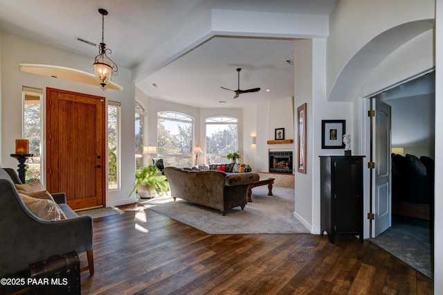 foyer entrance featuring ceiling fan, dark wood-type flooring, and a tile fireplace