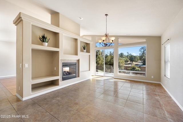 unfurnished living room featuring a multi sided fireplace, built in features, a notable chandelier, and tile patterned flooring