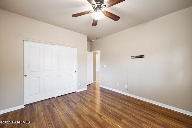 unfurnished bedroom with ceiling fan, dark wood-type flooring, and a closet