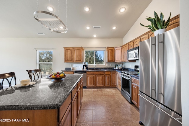 kitchen featuring a healthy amount of sunlight, a center island, light tile patterned floors, and appliances with stainless steel finishes