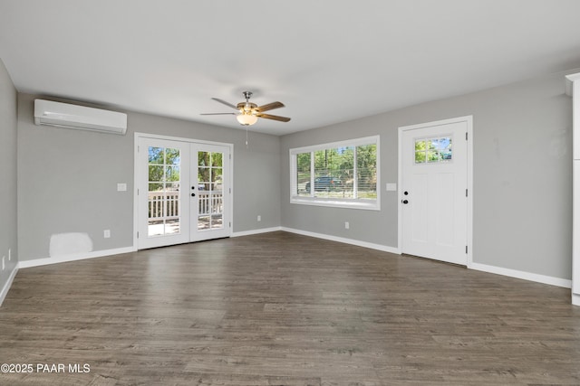 unfurnished living room with a wall unit AC, french doors, dark hardwood / wood-style floors, and plenty of natural light