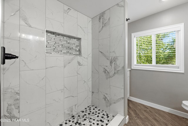 bathroom with hardwood / wood-style floors, a tile shower, and toilet