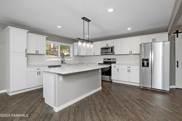 kitchen featuring stainless steel appliances, a kitchen island, white cabinets, and pendant lighting