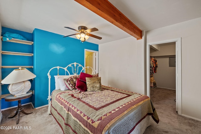 bedroom with a walk in closet, light carpet, beamed ceiling, a closet, and ceiling fan