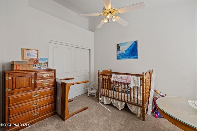 bedroom featuring ceiling fan, light colored carpet, a nursery area, and a closet